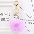 Detail of purple faux fur pompom keychain with unicorn charm and gold lobster clasp - Taro Purple