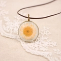 Vue macro d'un pendentif marguerite en bronze vintage sur dentelle délicate - Série de Fleurs Pressées Réelles / Orange