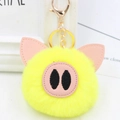 Close-up of bright yellow plush pig keychain with pink leather ears and gold metal clasp - Gold Key Chain Style / Yellow