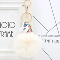 Detail of a white faux fur pompom keychain featuring a colorful unicorn with golden metal clasp - Off White
