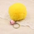 Detail of bright yellow faux fur pompom keychain with pink bell on beige lace background - 8cm Faux Rabbit Fur With Bell / Yellow