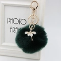 Close-up of elegant gold ballerina charm with rhinestones on dark green plush pom-pom - 8cm Faux Fur / Dark Green