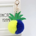 Detail of pineapple faux fur pompom keychain with green PU leaves and golden lobster clasp - 8cm / Yellow And Blue