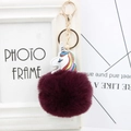 Detail of a deep purple faux fur pompom keychain with a rainbow unicorn PU leather charm - Fuschia