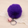 Macro view of dark purple faux fur pompom keychain with pink bell on beige fabric - 8cm Faux Rabbit Fur With Bell / Purple