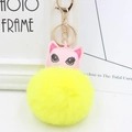 Détail d'un porte-clés chat en cuir rose avec un gros pompon jaune en fourrure synthétique - Jaune