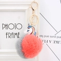 Close-up of a unicorn keychain with coral red and grey pompom on golden metal ring - Orange Red And Gray