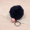Close-up of fluffy dark blue pom pom keychain with a pink bell on textured fabric - 8cm Faux Rabbit Fur With Bell / Navy Blue