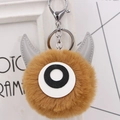 Macro-detail van de bruine monster pluche sleutelhanger met hoorn en zilveren sluiting - koffiekleur