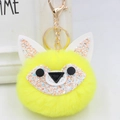 Close-up of bright yellow fluffy fox pompom keychain with golden metal ring and lobster clasp - Gold Key Chain Style / Yellow