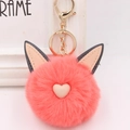 Détail macro du porte-clés pompon en peluche rose corail avec oreilles de chat et fermoir - Style Chaîne De Clé Or / Rouge Orangé
