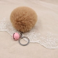 Detail of camel plush pom pom keychain with pink smiley bell on lace background - 8cm Faux Rabbit Fur With Bell / Khaki