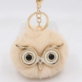 Detail of cute owl plush keychain with large glitter eyes and fluffy beige faux fur texture - Gold Key Chain Style / Nude White