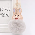 Close-up of cute rabbit plush keychain with grey faux fur pompom and gold metal ring - Light Gray