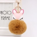 Detail of cute pink fox keychain with fluffy brown faux fur pom pom and golden metal clasp - Coffee
