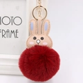 Close-up of fluffy dark red faux fur pompom rabbit keychain with golden metal clasp - Burgundy