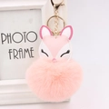 Detailed close-up of pink fox pom-pom keychain with gold hardware and embroidery - Pink