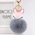 Detailed macro of fluffy grey faux fur ball keychain with pink leather fox ornament - Dark Gray