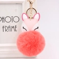 Detail view of a coral pink faux fur fox keychain with golden hardware for bags - Orange Red