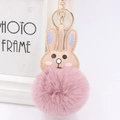 Close-up of pink fluffy pompom rabbit keychain with gold lobster clasp and leather ears - Dusty Pink
