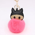 Close-up of pink fluffy pompom keychain with black faux leather pig head and golden clasp - Watermelon red