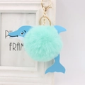 Close-up of a mint green fluffy pom pom dolphin keychain with gold metal clasp - Mint Green