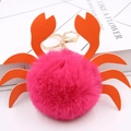 Détail macro d'un porte-clés crabe en fausse fourrure rose vif avec pinces en similicuir - Rose rouge