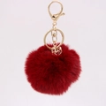 Detailed macro view of a red faux rabbit fur pompom keychain with golden crystal charms - Burgundy