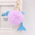 Close-up of pink plush dolphin keychain with golden lobster clasp on a white background - Taro Purple