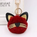 Detailed macro view of a red fluffy cat keychain with gold whiskers and a golden lobster clasp - Burgundy