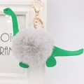 Cartoon green dinosaur keychain with a fluffy grey faux fur ball and gold metal clasp - Dinosaur Style / Light Gray