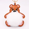 Détail d'un porte-clés ours en cuir marron avec pompon blanc doux et anneau doré - Style Chaîne De Clé Or / Blanc & Khaki