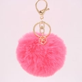 Close-up of pink faux rabbit fur pompom keychain with golden geometric cube pendant detail - Watermelon red