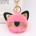 Detail of pink plush cat keychain with golden whiskers and leather ears on bag charm - Deep Pink