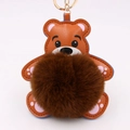 Détail d'un porte-clés ours en cuir marron avec pompon en fourrure et attache dorée - Style Chaîne De Clé Or / Brun & Khaki
