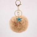 Detailed close-up of fluffy khaki pompom keychain with golden clasp and blue starfish charm - Khaki