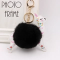 Close-up of black plush alpaca keychain with floral leather details and gold metal clasp - Black