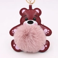 Vue détaillée d'un porte-clés ours en cuir bordeaux avec un pompon en peluche rose doux - Style Chaîne De Clé Or / Pâte de Haricots & Rouge
