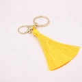 Gros plan d'un porte-clés à pompon en soie jaune vif avec fermoir mousqueton doré chic - Fermoir en Forme de 8 Doré / Jaune