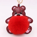 Détail d'un porte-clés ours en cuir rouge avec un grand pompon rouge et anneau doré - Style Chaîne De Clé Or / Rouge Vif