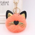 Close-up of bright orange plush cat ball keychain with golden whiskers and heart nose - Orange Red