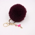 Detail of burgundy faux fur pompom keychain with golden clasp and pink flamingo charm - Purplish Red