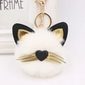 Detail of plush cat keychain showing white fur texture with gold whiskers and heart nose - Off White