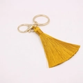 Détail du porte-clés à pompon jaune avec fermoir mousqueton doré pour sacs à main - Fermoir en Forme de 8 Doré / Or champagne