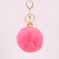 Close-up of pink fluffy pompom keychain with golden shell and pearl detail - Watermelon red
