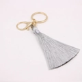 Détail d'un porte-clés à pompon gris clair avec mousqueton doré et anneau métal - Fermoir en Forme de 8 Doré / Gris