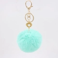 Close-up of mint green faux fur keychain with golden shell pendant and pearl detail - Mint Green