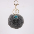 Detail of dark grey faux fur pompom keychain with golden metal ring and teal starfish charm - Dark Gray