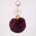 Detailed view of dark purple faux fur pompom keychain with golden shell pearl charm - Purplish Red