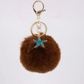 Close-up of fluffy brown faux fur pom pom with blue starfish charm and golden lobster clasp - Brown